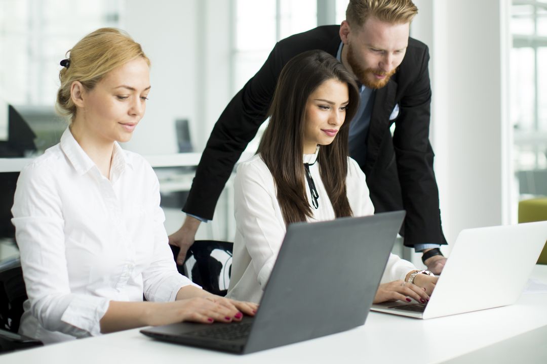 Team arbeitet gemeinsam am Laptop in einem hellen Büro