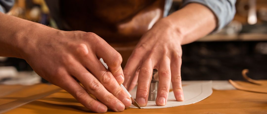 Hände bei präziser Handarbeit mit Leder